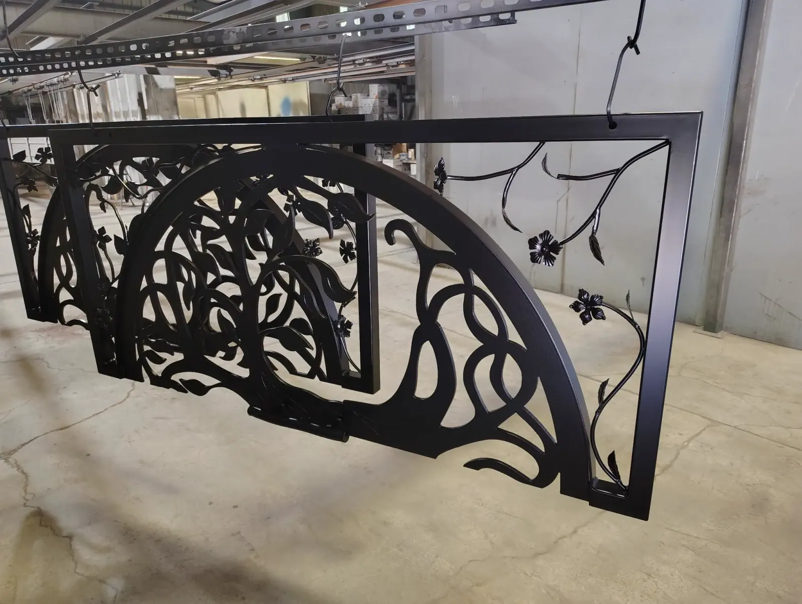 Black powder-coated arched decorative gate with vine and flower cut-outs