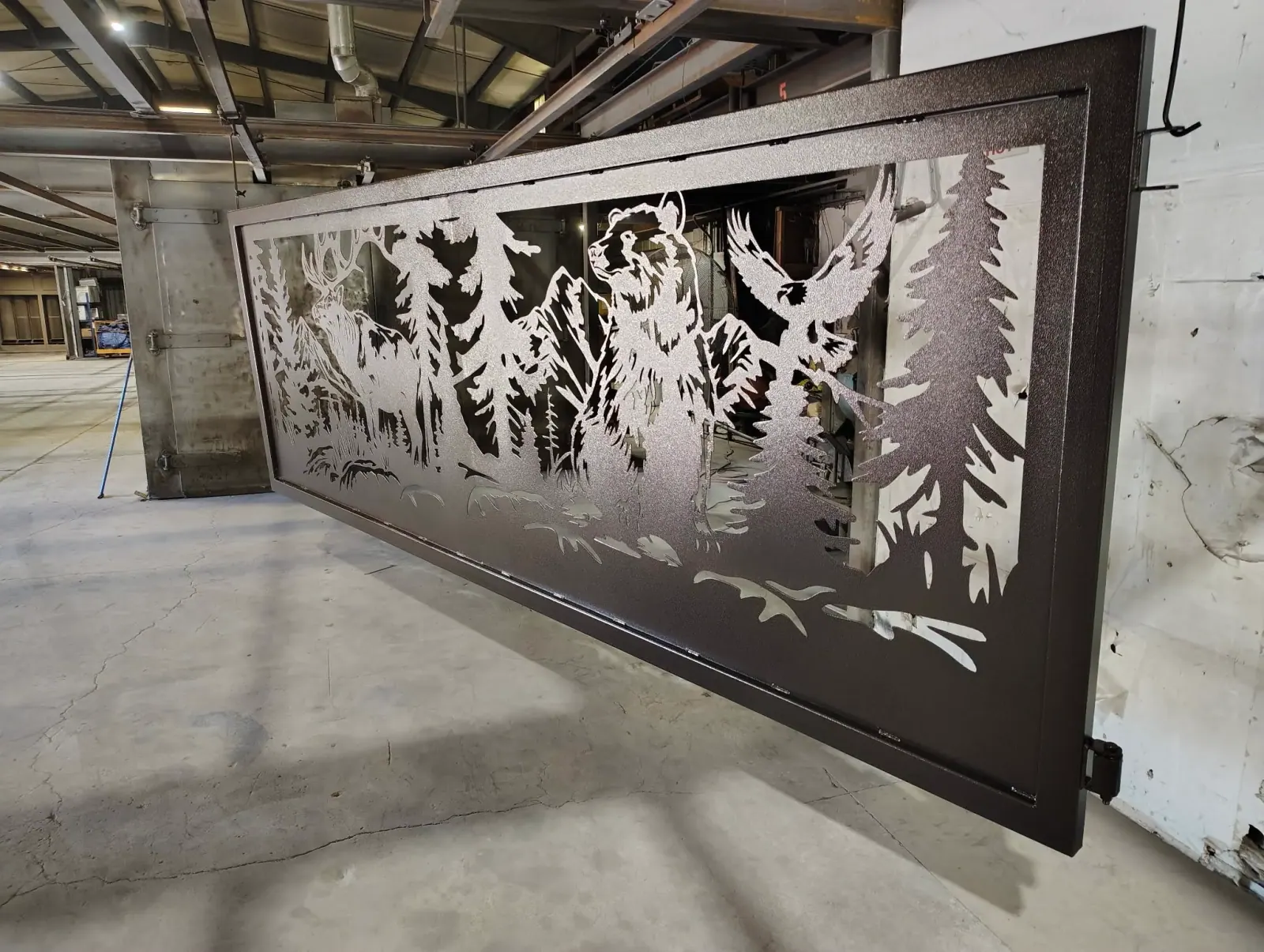 Large laser-cut elk and forest gate panel powder coated black in the M&M shop