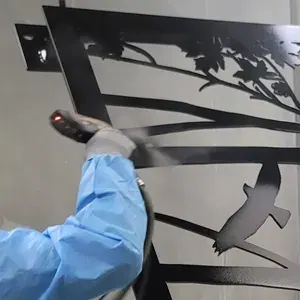 Powder gun coating a black decorative bird and branch panel