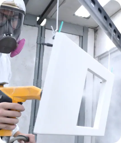 M&M coater in a respirator spraying white powder onto a panel in the booth